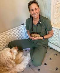 This image is of Katie Roe-Jarisch, DVM, sitting with a white and tan fluffy dog.